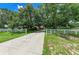 Gorgeous home featuring beautiful mature trees, a long concrete driveway, and a white fence at 2611 221St E St, Bradenton, FL 34211