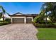 Beautiful single-story home with a two-car garage, brick driveway, and mature landscaping at 3512 Scrub Creek Run, Lakewood Ranch, FL 34211