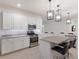 Bright kitchen featuring white cabinets, granite countertops, stainless steel appliances, and stylish pendant lighting at 3512 Scrub Creek Run, Lakewood Ranch, FL 34211