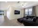Open living room featuring tile floors, neutral walls, black sectional couch, and a large window at 3512 Scrub Creek Run, Lakewood Ranch, FL 34211