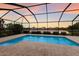 Inviting pool surrounded by a screened enclosure with lush landscaping and serene lake views at sunset at 3512 Scrub Creek Run, Lakewood Ranch, FL 34211