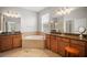 Bathroom with a tub surrounded by neutral tile, double sinks with granite countertops and mirrors and a stool at 358 River Enclave Ct, Bradenton, FL 34212