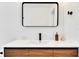 Bright bathroom featuring wood vanity with white countertop, a rectangular mirror, and modern black fixtures at 3856 Monica Pkwy, Sarasota, FL 34235