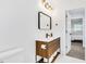 Bright bathroom featuring wood vanity with white countertop, a rectangular mirror, and modern gold light fixtures at 3856 Monica Pkwy, Sarasota, FL 34235