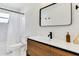 Bathroom featuring floating wood vanity with white countertop, modern black fixtures and shower with white curtain at 3856 Monica Pkwy, Sarasota, FL 34235