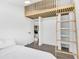Cozy bedroom with a wood ladder to a loft, open doorway, and light gray wood floors at 3856 Monica Pkwy, Sarasota, FL 34235
