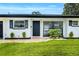 Close-up of the front entrance featuring a black door, manicured landscaping, and fresh exterior paint at 3856 Monica Pkwy, Sarasota, FL 34235