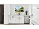 Modern kitchen with white cabinetry, stainless steel dishwasher, quartz countertops, and under-cabinet lighting at 3856 Monica Pkwy, Sarasota, FL 34235
