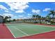 Well-maintained community tennis court with a net, bench, and views of residential buildings under a partly cloudy sky at 4131 Salernes Ave # 3051, Sarasota, FL 34233