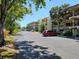 Exterior view of condo buildings and parking lot surrounded by mature trees and landscaping at 425 30Th W Ave # C104, Bradenton, FL 34205