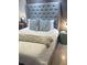 Inviting bedroom with a tufted headboard, patterned pillows, and wood-paneled wall at 4510 El Conquistador Pkwy # 105, Bradenton, FL 34210