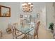 Bright dining room featuring modern chandelier, glass table, and natural light from the window at 4613 Sweetmeadow Cir, Sarasota, FL 34238
