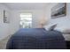 Bedroom featuring light wood floors, a window with blinds, and a side table with lamp at 466 Sunnyside Dr, Venice, FL 34293