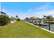 Home's backyard with lush green grass along the water and a boat dock at 524 Schooner Ln, Longboat Key, FL 34228