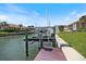 Dock with boat lift on a sunny day with waterfront homes and a blue sky in the background at 524 Schooner Ln, Longboat Key, FL 34228