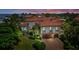 Aerial view of a waterfront Mediterranean home with a tile roof, three-car garage and lush landscaping at 524 Schooner Ln, Longboat Key, FL 34228