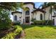 Beautiful Mediterranean-style home with lush landscaping, arched entryway, and well-manicured lawn at 524 Schooner Ln, Longboat Key, FL 34228
