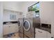 Well-equipped laundry room with front-loading washer and dryer, storage cabinets, and a sink area at 524 Schooner Ln, Longboat Key, FL 34228