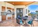 Covered outdoor kitchen featuring grill, tile backsplash, dining table and pool in the background at 524 Schooner Ln, Longboat Key, FL 34228