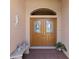 Elegant double front doors with decorative glass inserts, complemented by a quaint bench and potted plant at 6532 Copper Ridge Trl, Bradenton, FL 34201