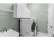 Laundry room with modern washer and dryer, overhead storage, and a utility sink at 6532 Copper Ridge Trl, Bradenton, FL 34201