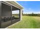 Well-maintained backyard with green grass, screen enclosed porch, and partial view of other homes at 6708 162Nd E Pl, Parrish, FL 34219
