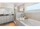 Bright bathroom features a tub with tile surround and glass door, plus a gray vanity with a dark countertop at 6708 162Nd E Pl, Parrish, FL 34219