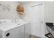 Functional laundry room with white washer, dryer, storage shelves, and a door at 6708 162Nd E Pl, Parrish, FL 34219