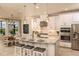Bright kitchen featuring an island with seating, white cabinetry, modern appliances, stylish pendant lights, and an adjacent dining area at 6916 Prairie Oak Way, Nokomis, FL 34275