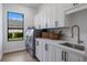 Modern laundry room with stainless steel washer and dryer, white cabinets, and a window at 7011 Belmont Ct, Lakewood Ranch, FL 34202