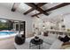 Open-concept living room featuring exposed beam ceilings, modern furnishings, and access to a pool at 7011 Belmont Ct, Lakewood Ranch, FL 34202
