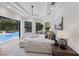 Bright main bedroom with pool access, tray ceilings, and a seating area with a view of the backyard at 7011 Belmont Ct, Lakewood Ranch, FL 34202