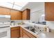Traditional kitchen featuring stainless steel sink, appliances, and wood cabinetry with a pass-through window to the dining area at 7218 Cloister Dr # 7218, Sarasota, FL 34231