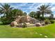 A beautiful community sign for River Strand set amid lush landscaping, palm trees, and a rock waterfall feature at 7607 Grand Estuary Trl # 302, Bradenton, FL 34212