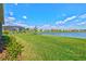 An expansive green backyard, partially bordering a lake, showcases a screened pool enclosure and lush shrubbery at 8107 Slipway Dr, Sarasota, FL 34240