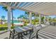 A community outdoor seating area with tables, chairs, and a view of the pool under a shaded pergola at 8107 Slipway Dr, Sarasota, FL 34240