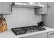 Close-up of a gas cooktop with stylish backsplash and range hood at 845 Burlington N Ave, St Petersburg, FL 33701