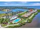 Aerial view of waterfront homes, a marina, a pool, a river, and tennis courts at 1264 Riverscape St # B, Bradenton, FL 34208