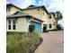 Two story yellow and cream building featuring a teal garage door, manicured landscaping, and a brick driveway at 1264 Riverscape St # B, Bradenton, FL 34208