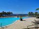 Beautiful community pool featuring sun loungers, palm trees, and serene lake views at 1264 Riverscape St # B, Bradenton, FL 34208