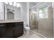 Bright bathroom featuring a glass shower, neutral tile, and a dark vanity with double sinks at 1719 Kenilworth St, Sarasota, FL 34231