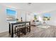 Open-concept living area with new wood flooring, a dining table, and comfortable seating by large, sunlit windows at 221 Duxbury Ave, Port Charlotte, FL 33952