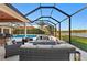 Screened-in patio featuring an outdoor kitchen, outdoor seating, a pool, and a serene lake view at 251 Dove Trl, Bradenton, FL 34212