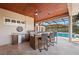 Covered outdoor kitchen with bar seating, stainless steel grill, and views of the backyard pool at 251 Dove Trl, Bradenton, FL 34212