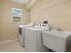 Bright laundry room featuring a washer, dryer, and utility sink with a wire shelf for storage at 27255 Deep Creek Blvd, Punta Gorda, FL 33983