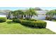 Beautifully landscaped front yard with lush green bushes, palm trees and a manicured lawn at 3870 Alamanda Dr, Sarasota, FL 34238