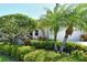 Beautifully landscaped front yard with lush green bushes, palm trees, and a charming entry area at 3870 Alamanda Dr, Sarasota, FL 34238