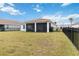 Serene backyard featuring a lush lawn and a charming screened-in patio, surrounded by a sleek black fence for privacy and enjoyment at 412 Daylily Blvd, Nokomis, FL 34275