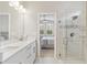 Bright bathroom showcases a dual vanity, and a glass shower with views into the primary bedroom at 412 Daylily Blvd, Nokomis, FL 34275