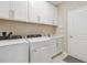 Bright laundry room featuring a Whirlpool washer and dryer, white cabinets, and a sleek countertop with under cabinet lighting at 412 Daylily Blvd, Nokomis, FL 34275